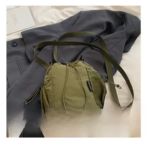 Detail of army green nylon bucket bag featuring side mesh pocket and drawstring closure