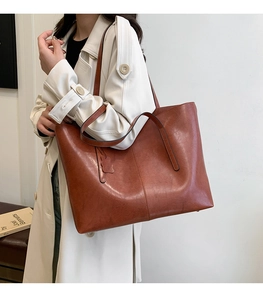 Detail of a large brown leather tote bag with vintage texture and double handle design