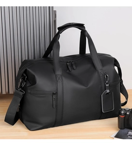 Close-up of black waterproof travel bag with reinforced handles and leather luggage tag