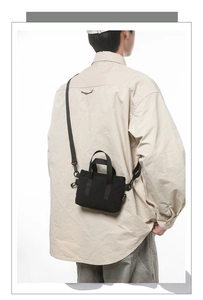 Rear view of model wearing black nylon mini tote bag with adjustable shoulder strap
