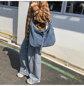 Outdoor street style shot showing texture and drape of a large blue denim tote bag