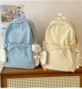 Detail of light blue and beige school backpacks with cute bow and cloud charms
