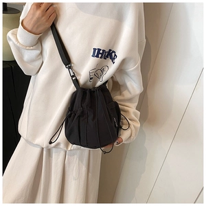 Detail of a black nylon drawstring bucket bag showing the side logo and strap texture