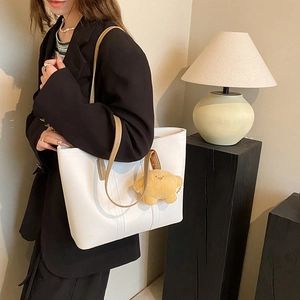Minimalist white leather tote bag with brown straps and cute yellow plush charm