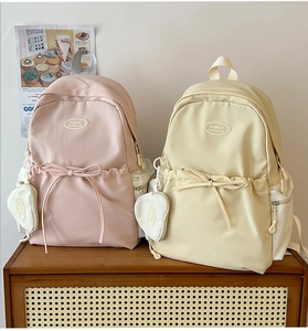 Detail of pink and beige backpacks featuring bow drawstring and heart coin pouches