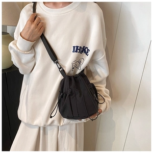 Detail view of black drawstring bucket bag with mesh pocket and adjustable shoulder strap