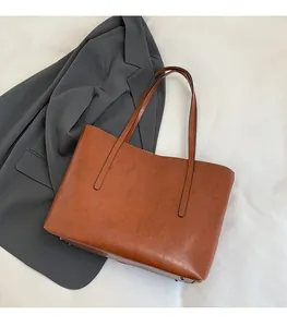 Detail of a brown leather tote bag with reinforced metal studs on a smooth white surface