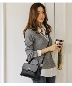 Detailed view of a black lychee-grain crossbody bag with a golden turn-lock closure