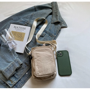 Détail d'un sac à bandoulière beige imperméable avec poche frontale et sangle en nylon