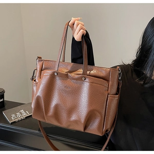 Détail du sac cabas marron vintage montrant la texture froissée et les poches avant
