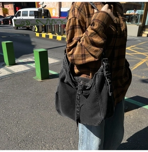 Street style view of a black denim hobo bag featuring contrast stitching and eyelet straps