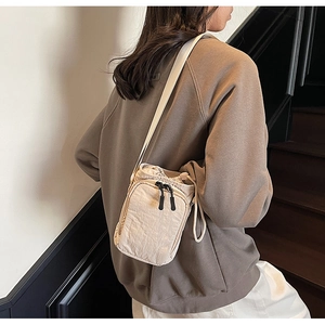 Sac bandoulière beige en nylon pour gourde avec cordon porté par un mannequin