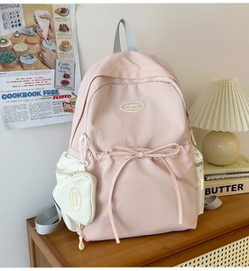 Detailed close-up of pink and white nylon backpack with bow drawstring and side pouch