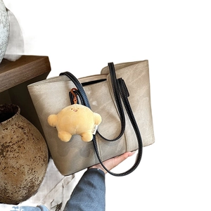 Large taupe leather tote bag with black straps and a plush yellow star charm