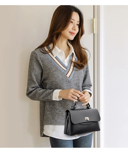 Detail of black pebbled leather handbag with gold twist lock and protective metal feet