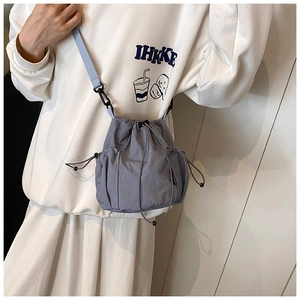 Detail of grey-blue nylon bucket bag with adjustable drawstring and side mesh pocket