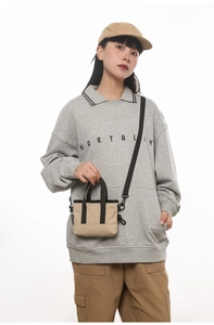 Urban minimalist beige nylon crossbody bag with black straps worn by model
