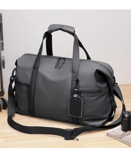 Close-up of waterproof dark gray travel bag with dual zippers on a light wood surface