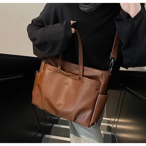 Détail du cabas en cuir marron foncé avec poche avant à rivets et compartiment latéral