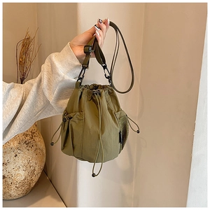 Detail of olive green nylon drawstring bucket bag showing mesh pocket and adjustable strap