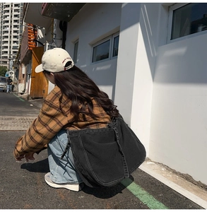 Outdoor shot of a black canvas crossbody bag with white stitching in a street style look