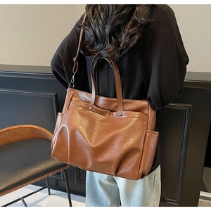 Vue détaillée de la texture en cuir marron et des rivets métalliques de ce grand sac cabas