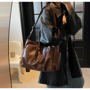 Gros plan du cabas vintage marron montrant le cuir grainé et la poche latérale pratique
