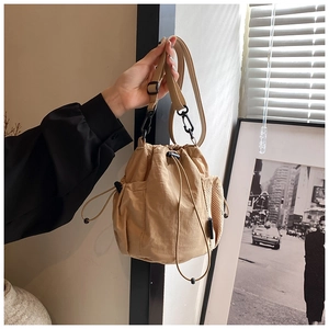 Detail of khaki nylon drawstring bucket bag showing side mesh pocket and adjustable strap