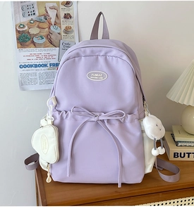 Detail of lavender nylon backpack featuring bow ribbons and white plush charms