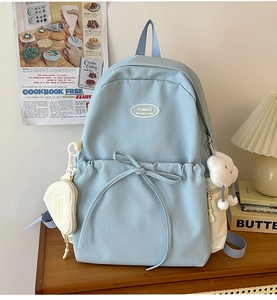 Detail of light blue backpack featuring a drawstring bow and plush cloud charm