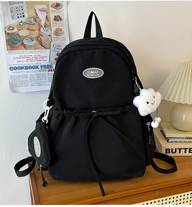 Detail of black nylon backpack with brand logo, drawstring pocket and cute plush charm
