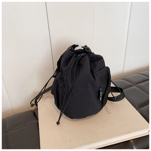 Detail of black nylon drawstring bucket bag featuring a side mesh pocket and side brand label