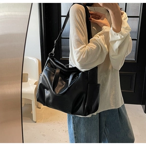 Gros plan d'un sac cabas en cuir noir avec texture grainée et poche latérale sur modèle
