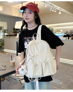 Close-up of cream nylon backpack featuring cute bow drawstring and star plush pendant