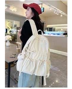 Detail of off-white school backpack with drawstring pockets and a plush bear charm
