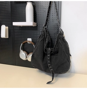 Detail view of black denim hobo bag featuring white contrast stitching and grommeted strap