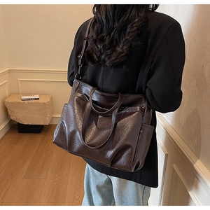 Détail du grand sac cabas marron montrant la texture cuir brillant plissé et poche latérale