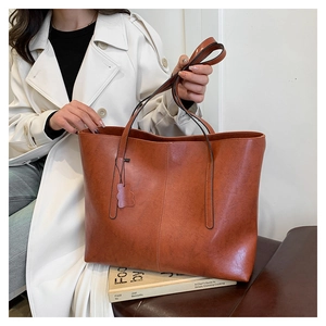Detail of caramel faux leather tote bag showing smooth texture and cute bear pendant charm