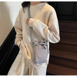 Détail du sac bandoulière en nylon gris clair avec cordon de serrage et zip de poche