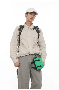 Look outdoor casual con mini borsa a tracolla verde acceso e pantaloni cargo scuri