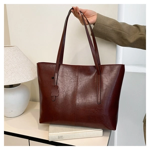 Detailed macro view of retro burgundy tote bag with glossy leather texture and straps