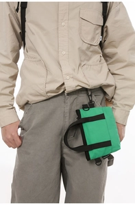 Detail of bright green nylon messenger bag with black strap and metallic D-ring on model