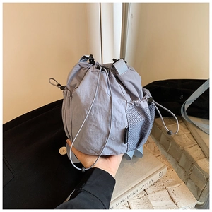 Detail of blue-grey nylon drawstring bucket bag with side mesh pocket and adjustable cord