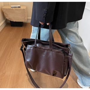 Gros plan du fourre-tout en cuir marron vintage montrant la texture et la poche avant