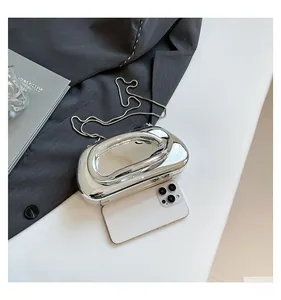 Detail of silver mirror acrylic clutch bag with metal chain strap on minimalist background