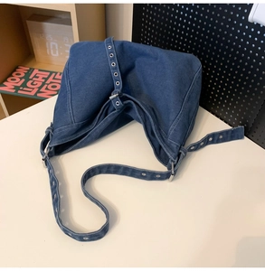Close-up of denim hobo bag with vintage silver metal eyelets on the shoulder strap