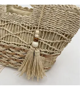 Detalle de la textura de paja tejida y borla bohemia con cuentas de madera del bolso