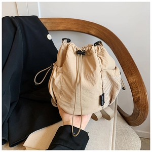 Detail of khaki nylon bucket bag showing drawstring closure and white mesh side pocket