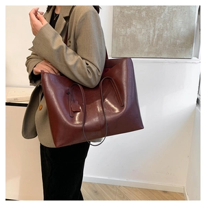 Close-up of deep red large tote bag featuring slim straps and a cute bear charm pendant