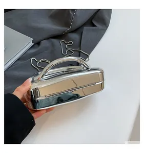 Detailed close-up of metallic silver hard shell clutch bag with integrated metal handle